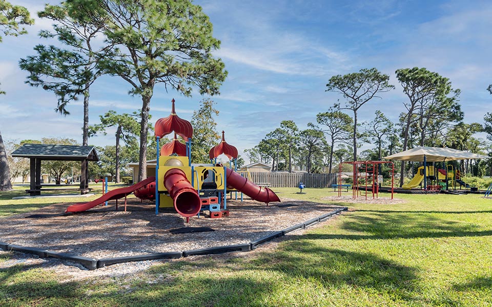 a playground with a red and yellow slide in a park