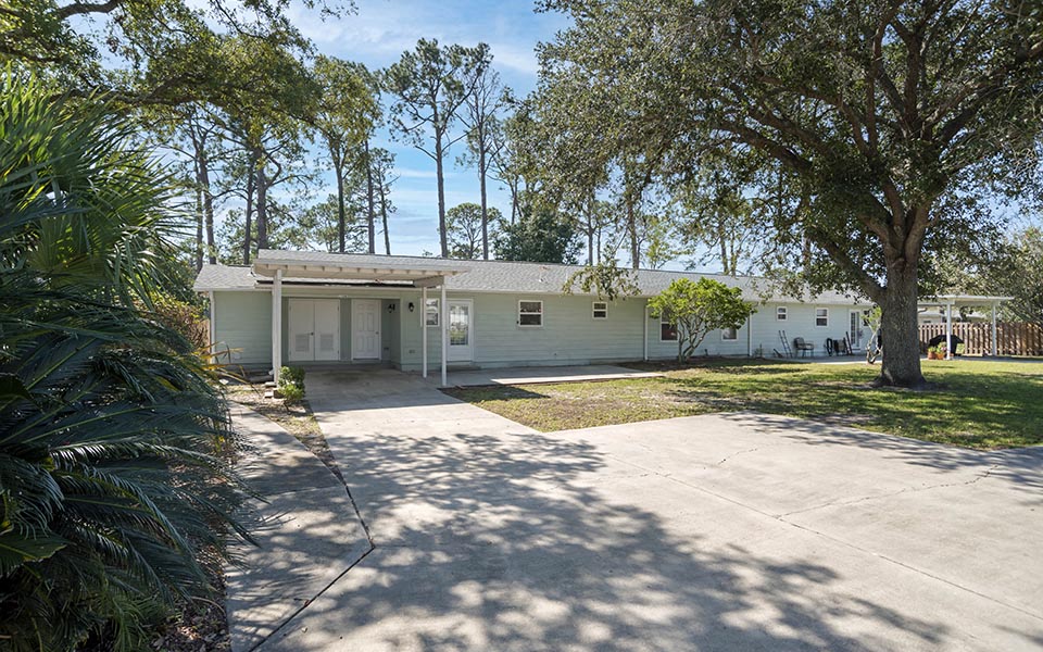 a white house with a driveway and trees