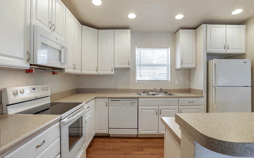 a kitchen with white cabinets and a stove and a sink