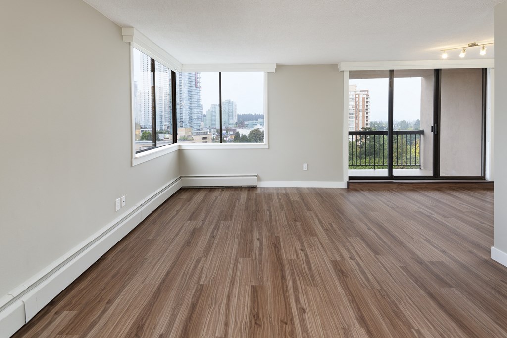 an empty living room with wood flooring and a balcony