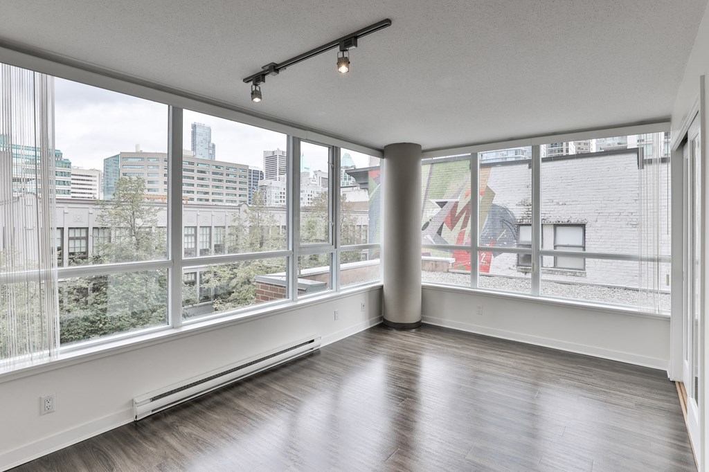 an empty living room with large windows and wood floors