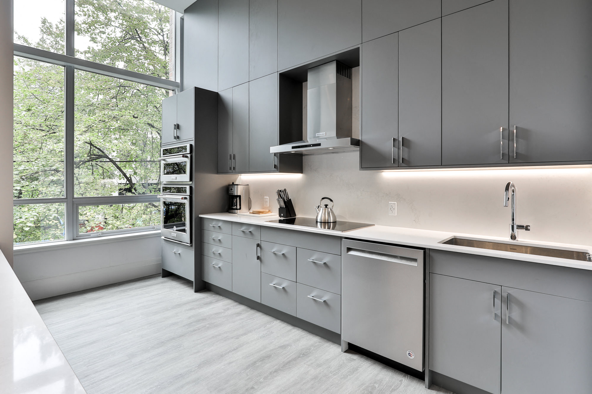 a kitchen with gray cabinets and a large window