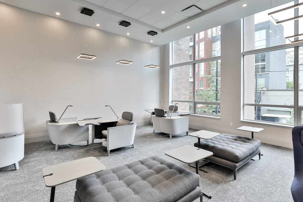 a room with couches tables and chairs and large windows