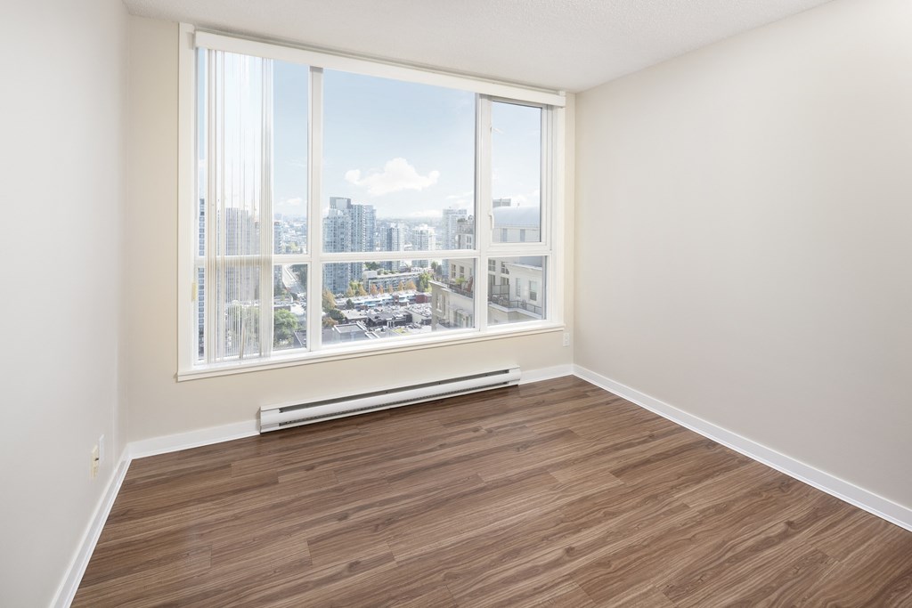 an empty room with a large window and wooden floors