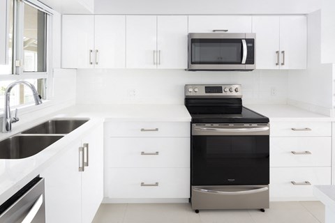 a kitchen with white cabinets and a black stove and microwave
