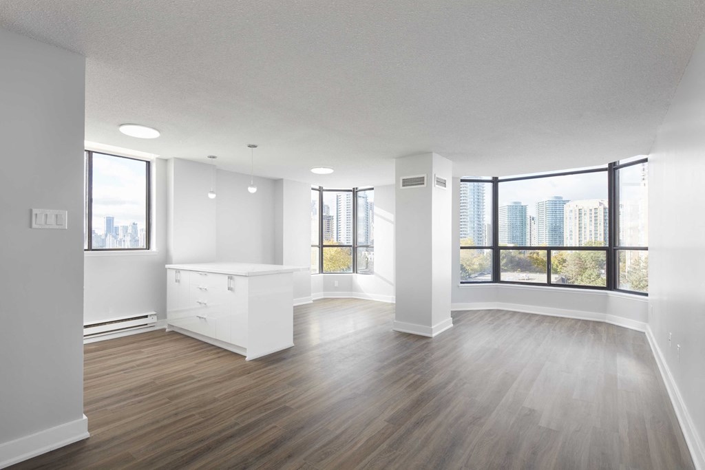 an empty living room with a large window and a kitchen