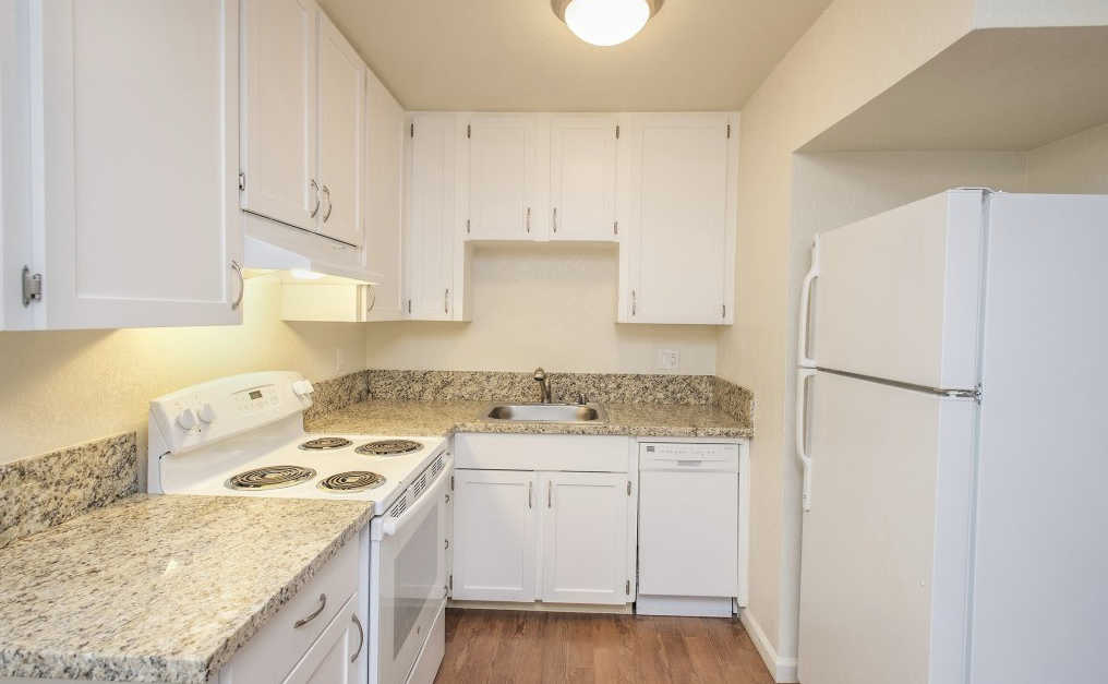 A kitchen with white cabinets and granite countertops.