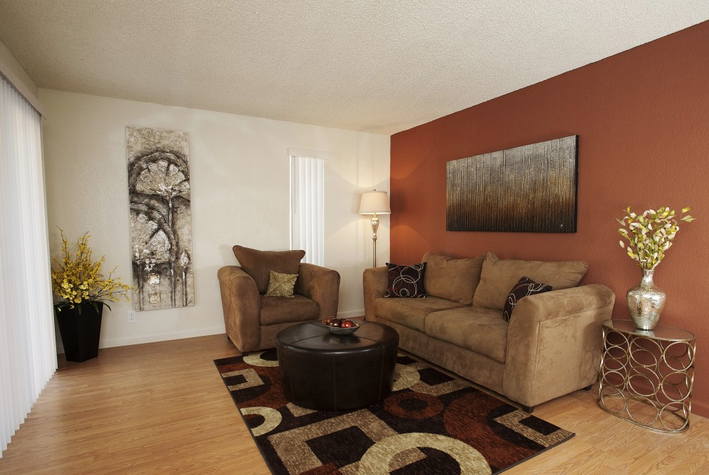 A living room with a brown couch, a brown chair, and a brown ottoman.