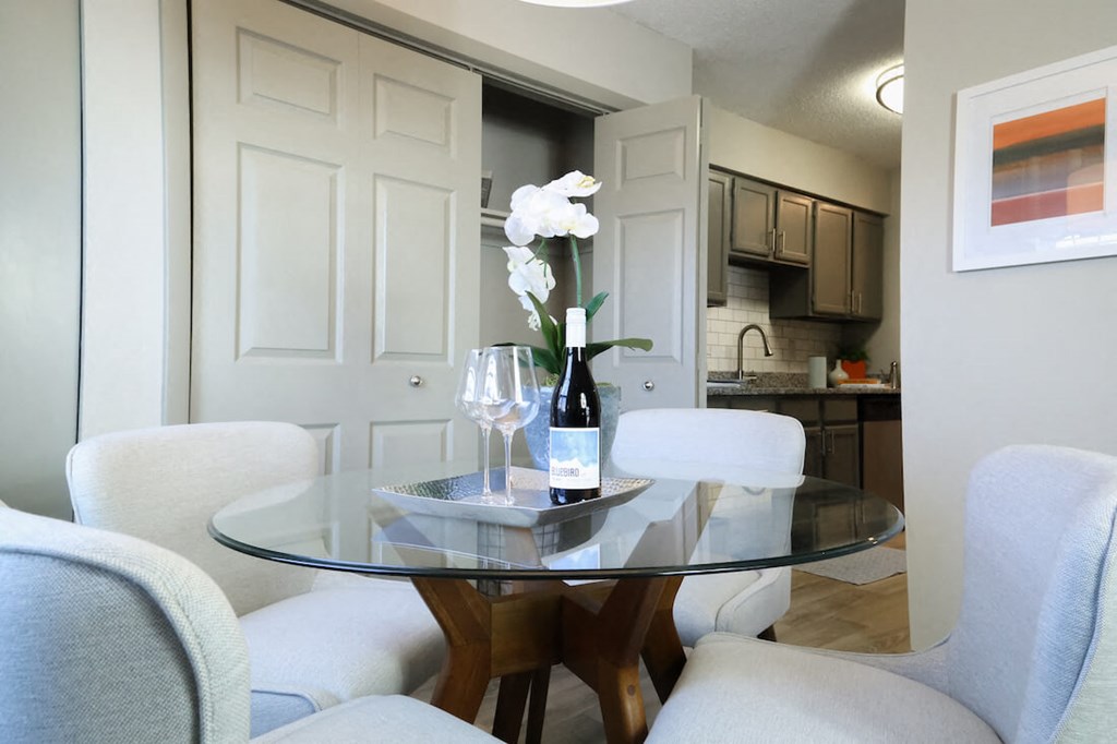 a dining room with white chairs and a table with a vase of flowers