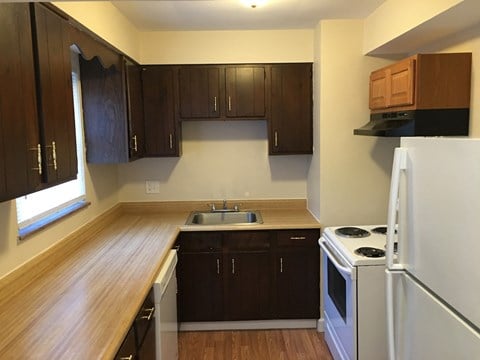 a kitchen with white appliances and wooden cabinets and a window