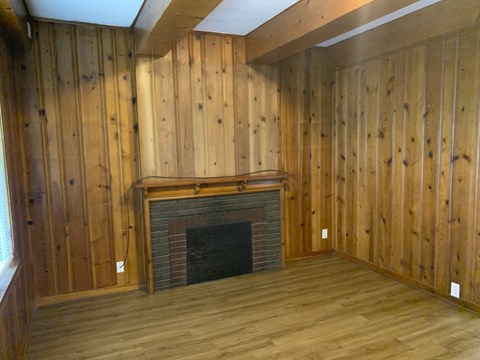 a living room with a fireplace and wooden walls