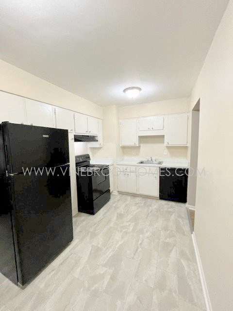 a kitchen with white cabinets and a black refrigerator
