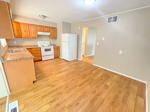 an empty kitchen with wood floors and a refrigerator