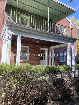a front porch of a brick house with a balcony