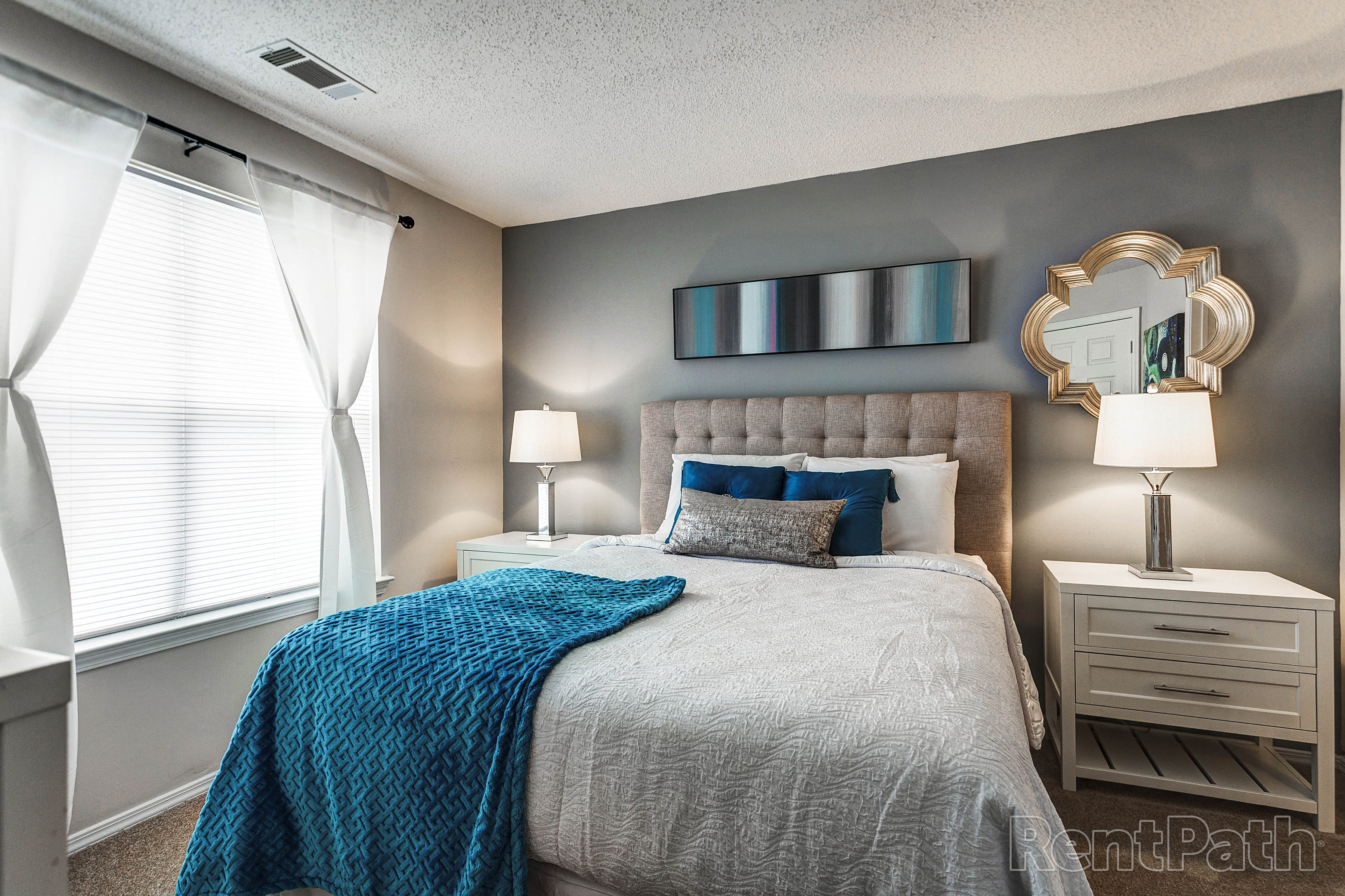 a bedroom with a bed with a blue blanket and pillows