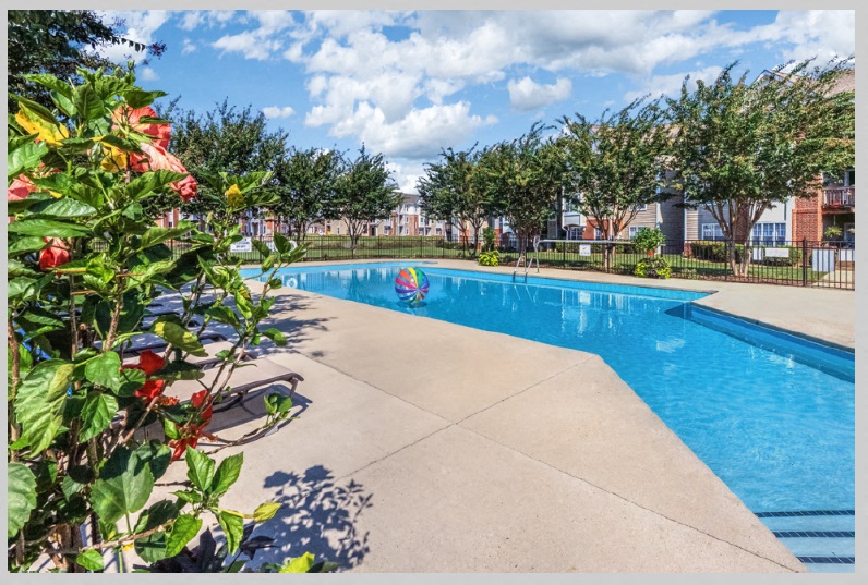 a swimming pool with trees and a building in the background