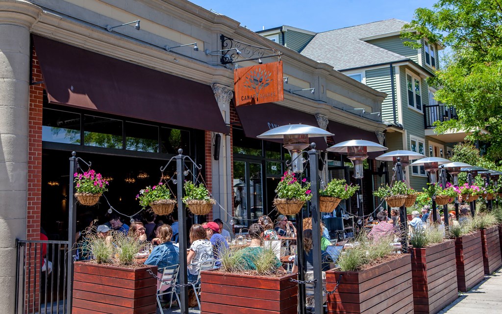 people sitting at tables outside of a restaurant