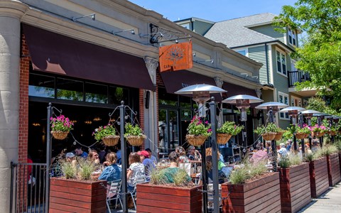 people sitting at tables outside of a restaurant