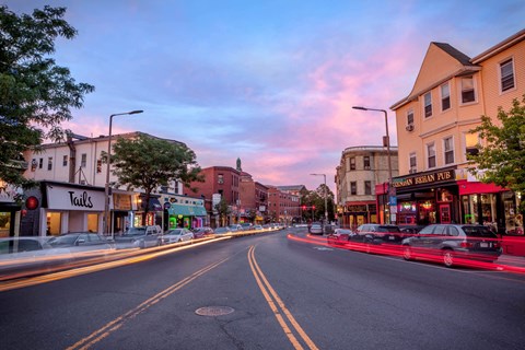 a city street at sunset with cars driving down it