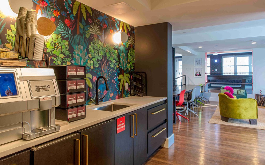 a kitchen with a sink and a coffee machine in a room with a dining room