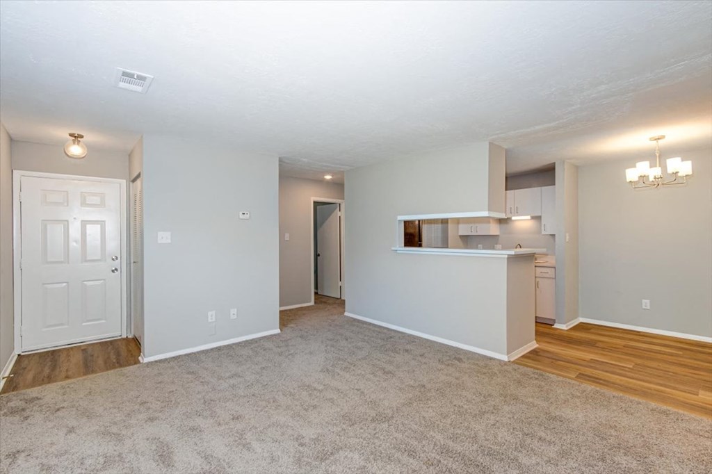 an empty living room and kitchen with a door to the bathroom