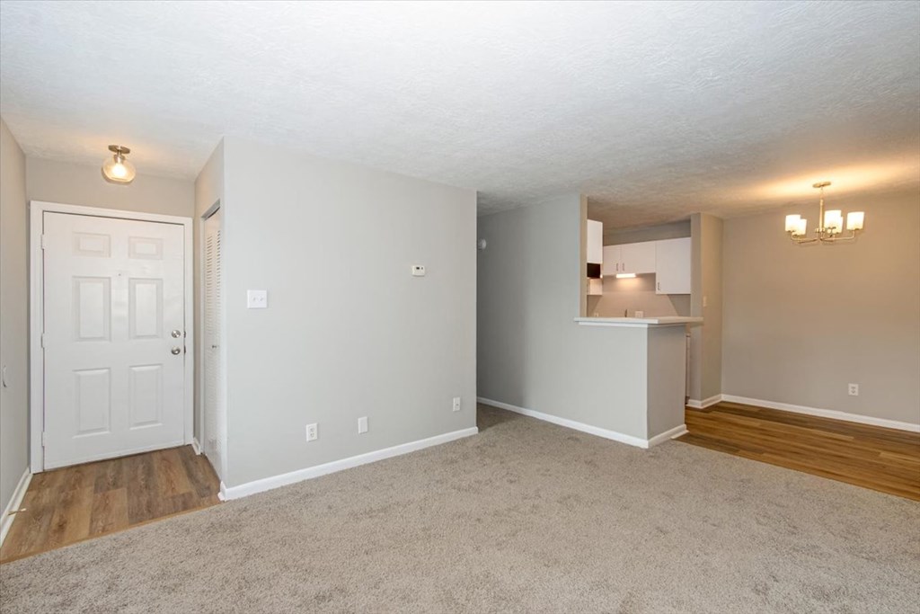 an empty living room and kitchen with a white door