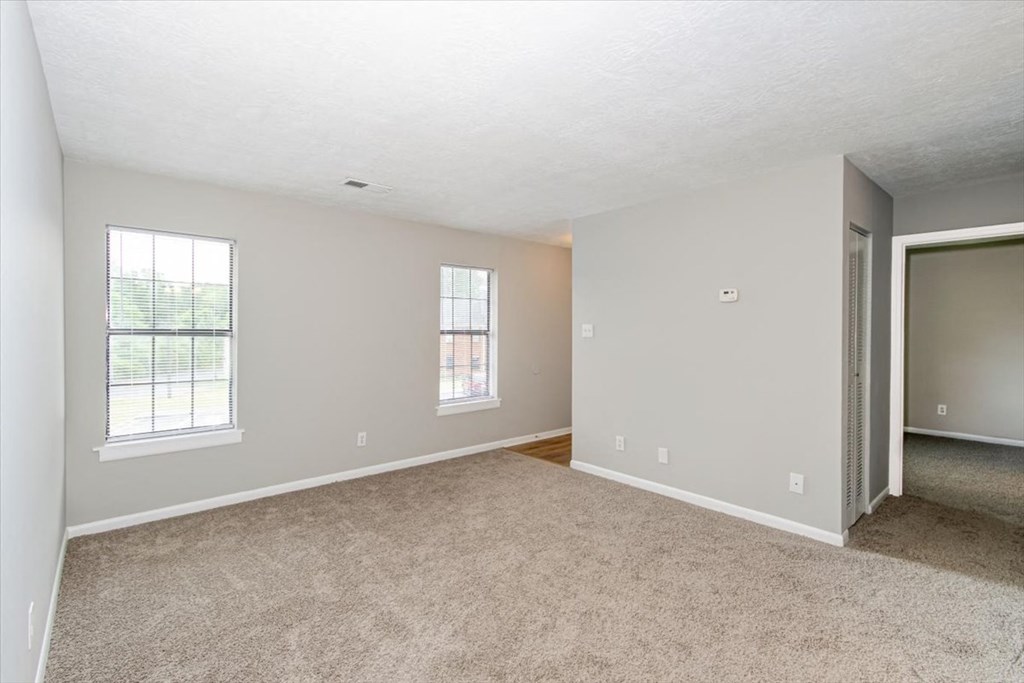the living room and dining room of an empty home with carpet