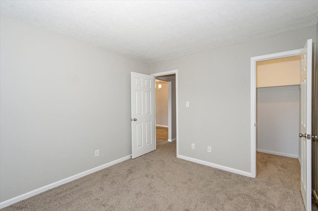 a bedroom with a door to a hallway and a closet