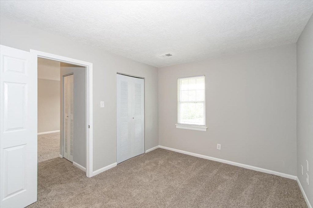 an empty living room with a door to a closet