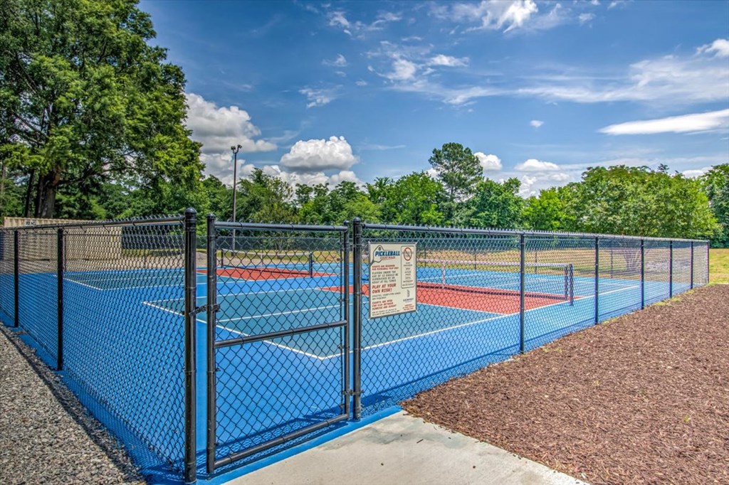 a tennis court with a fence and a sign on the gate