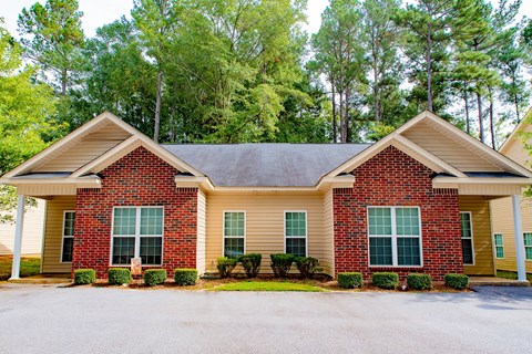 a red brick house with green trees in the background