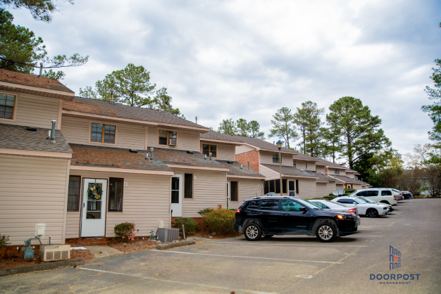 a row of apartments with cars parked in a parking lot