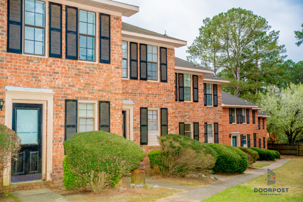 a large brick apartment building with black windows and a sidewalk