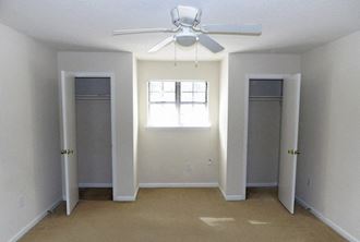 an empty room with a ceiling fan and two closets