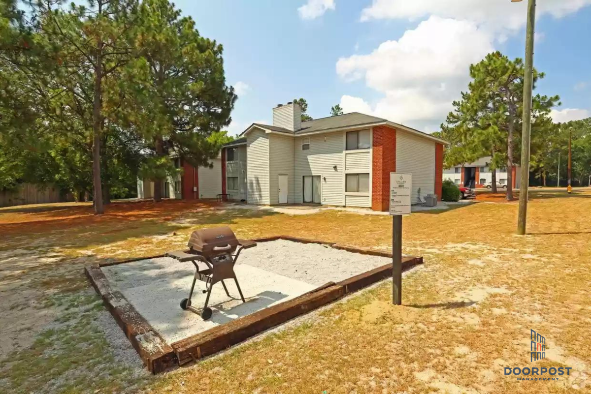 a backyard with a patio with a grill and a house in the background