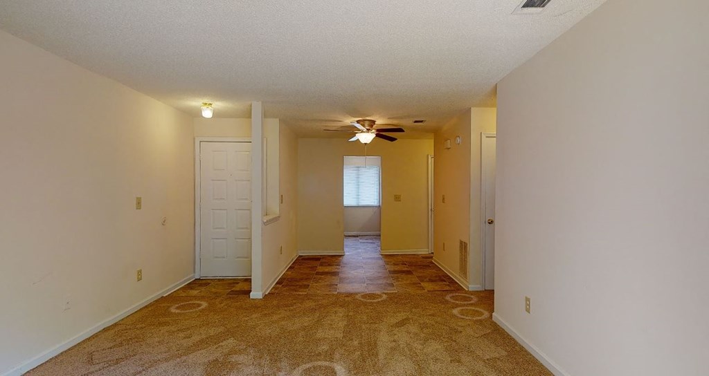 a empty living room with a ceiling fan      and a door