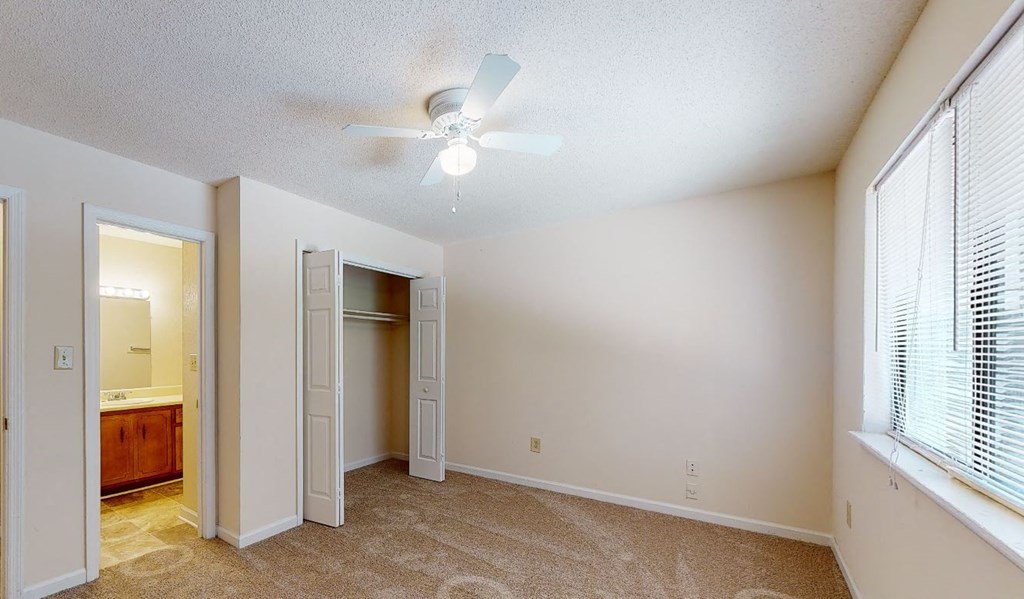 an empty living room with a ceiling fan and a closet