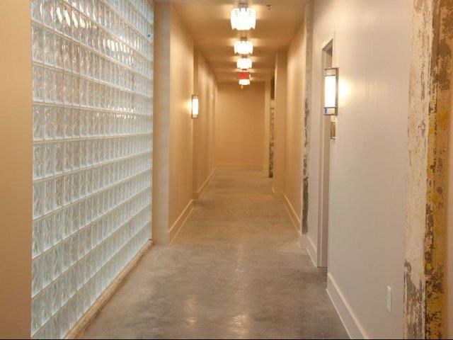 a long hallway with white tiles on the wall and a corridor with lights