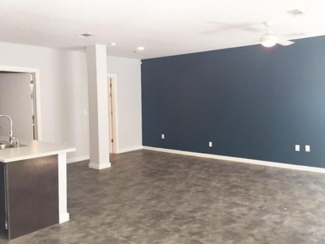 an empty living room with a blue wall and a kitchen