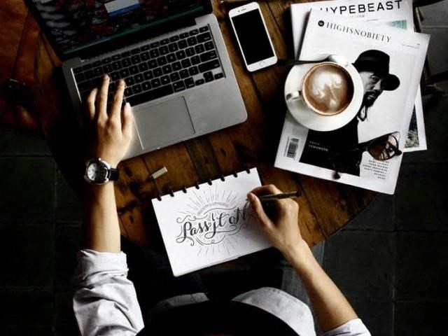 a person sitting at a table with a laptop and a cup of coffee