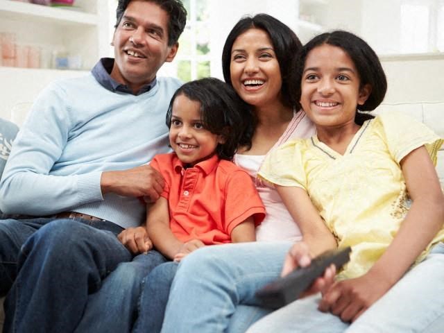 a family sitting on a couch with a remote control