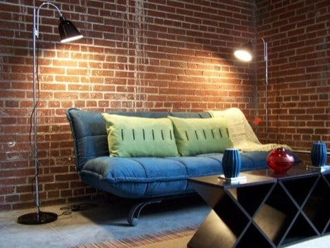 a living room with a couch and a brick wall