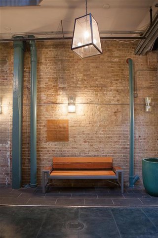 a wooden bench in front of a brick wall