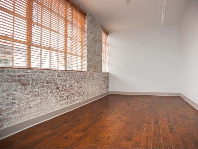 an empty room with a brick wall and wood floors