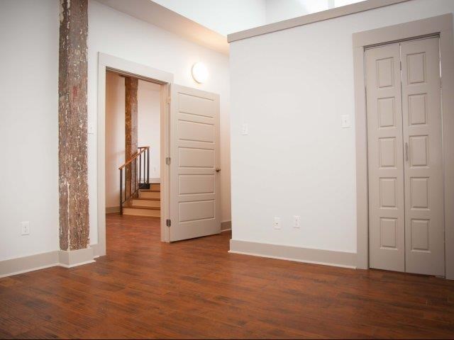 an empty living room with a door and a staircase