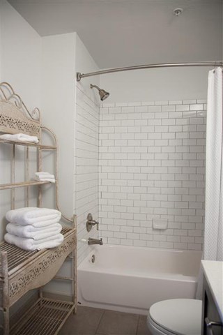 a white bathroom with a tub and a toilet and some towels