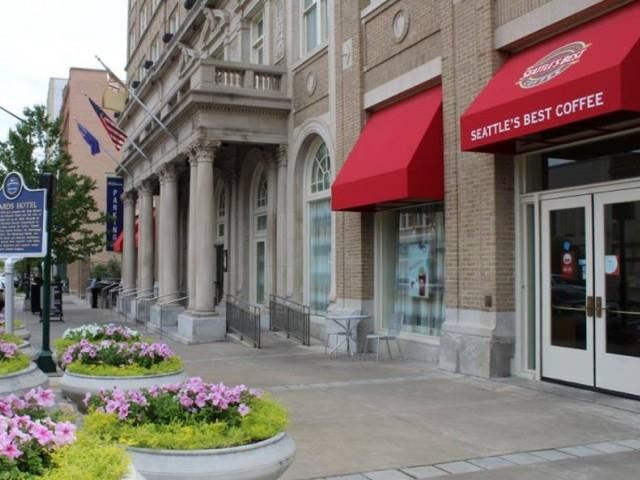a city street with a coffee shop and flowers on the sidewalk