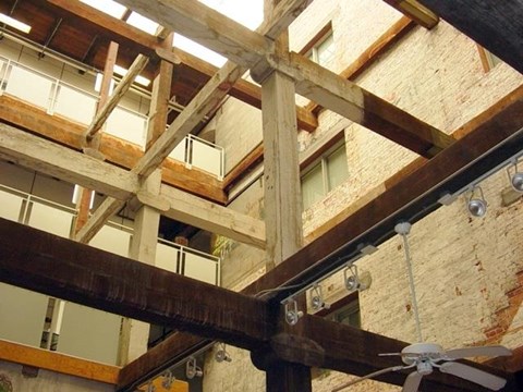 A ceiling fan is mounted on a wooden beam.