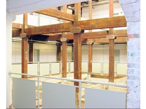A wooden beam structure is supported by white pillars.