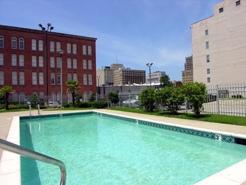 A swimming pool in front of a red brick building with a number 3 on the side.